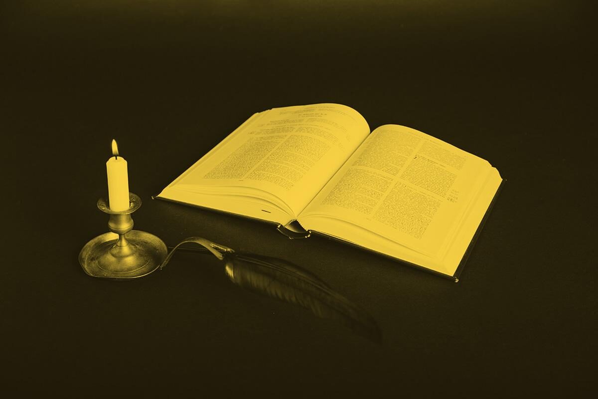 An open book lit by a candle